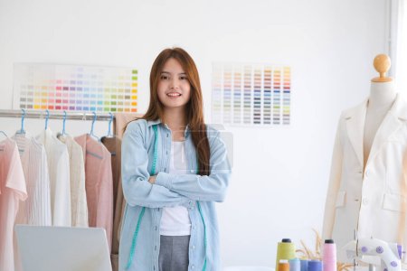 Photo for A professional fashion designer standing in her tailor shop with arms folded confident and looking at camera with a big smile. She is smiled with confident. - Royalty Free Image