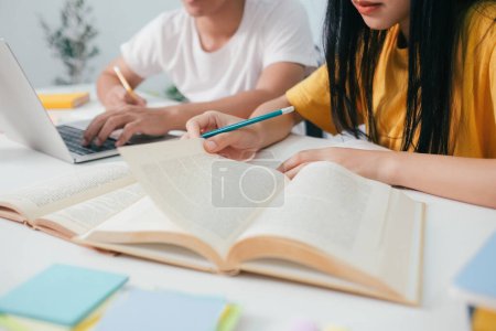 Photo for Close up young asian university students are studying for an exam. There are tutor books with friends. They are classmates that try to help each other. They have been tutoring for many hours in the - Royalty Free Image