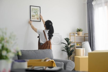 Téléchargez les photos : Jeune femme asiatique décoration nouvelle maison tout en emménageant dans une nouvelle maison ou appartement. - en image libre de droit