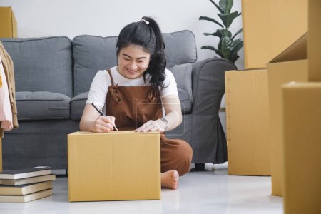 Photo for Happy single young woman packing or unpacking cardboard boxes while moving to new house or new apartment. New beginnings emotion. Living alone. Modern female people in moving home apartment leisure indoor activity alone. - Royalty Free Image