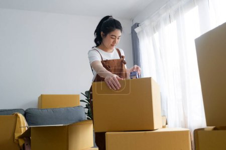 Photo for Happy single young woman packing stuff among plenty of cardboard boxes cardboard boxes while moving to new house. Living alone. Modern female people in moving home apartment leisure indoor activity - Royalty Free Image