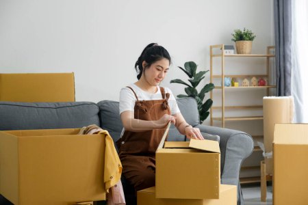 Photo for Happy single young woman packing or unpacking cardboard boxes while moving to new house or new apartment. New beginnings emotion. Living alone. Modern female people in moving home apartment leisure - Royalty Free Image
