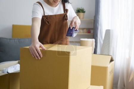 Photo for Happy single young woman packing stuff among plenty of cardboard boxes cardboard boxes while moving to new house. Living alone. Modern female people in moving home apartment leisure indoor activity - Royalty Free Image