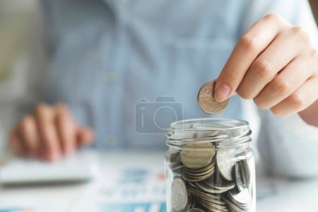 Photo for Woman hand putting coin on saving jar. Saving money wealth and financial concept, Business, finance, investment, Financial planning. - Royalty Free Image