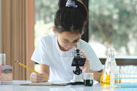 Foto de Chica de la escuela mirando a través del microscopio. Linda chica utiliza microscopio. Programa STEM de Ciencia, Tecnología, Ingeniería y Matemáticas. - Imagen libre de derechos