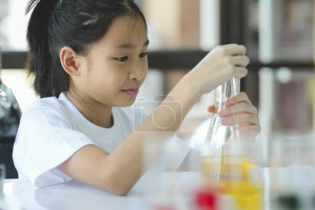 Téléchargez les photos : Schoolgirl dépose une substance liquide dans le tube à essai avec une longue pipette en verre dans le laboratoire scientifique chimique. - en image libre de droit