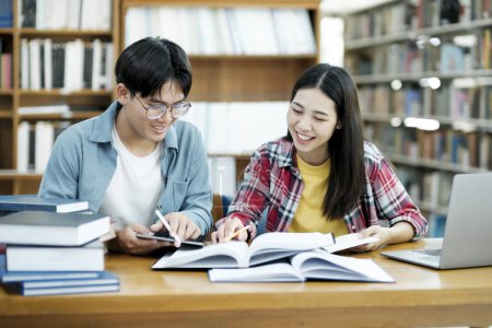 Photo for Young students campus helps friend catching up and learning. University students in cooperation with their assignment at library. Group of young people sitting at table reading books. Education and - Royalty Free Image