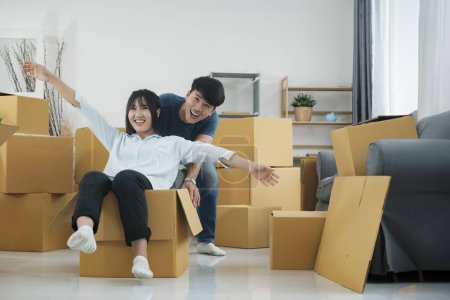 Photo for Happy couple is having fun with cardboard boxes in new house at moving day. - Royalty Free Image
