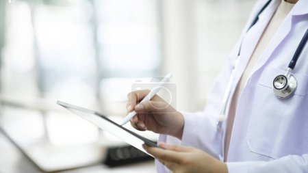 Photo for Cropped shot of a doctor using a digital tablet. Close up of doctor hands using digital tablet at clinic. Closeup of doctor in labcoat and stethoscope holding digital tablet. Doctor working on a - Royalty Free Image