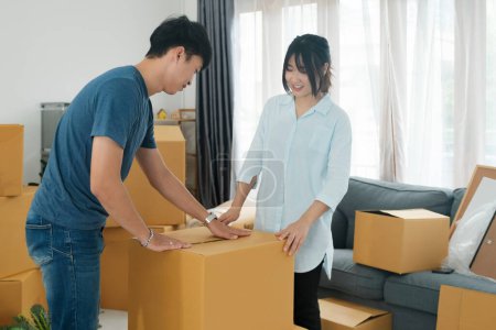 Photo for Young married couple moving into new home. Theyre unpacking or packing card boxes with their accessories. - Royalty Free Image