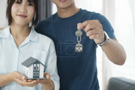 Téléchargez les photos : Heureux jeune couple achetant une nouvelle maison recevant les clés. Propriétaire de la maison concept immobilier. - en image libre de droit