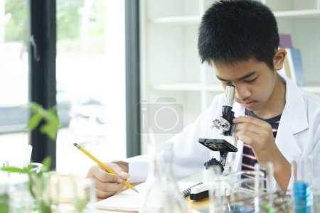 Photo for Young elementary schoolboy concentrates on his science project, exploring the world through a microscope. This image captures the essence of education, curiosity, and hands-on learning. Ideal for STEM - Royalty Free Image