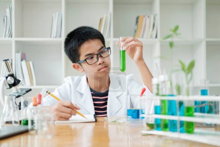 Foto de Asiático escolar primaria aprender química de la ciencia con tubo de ensayo haciendo experimento en el laboratorio de la escuela. educación, ciencia, química y concepto infantil. Desarrollo temprano de los niños. Ideal - Imagen libre de derechos