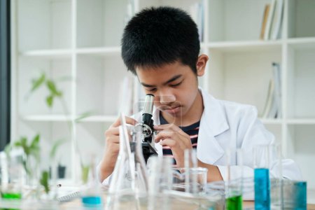 Photo for Young elementary schoolboy concentrates on his science project, exploring the world through a microscope. This image captures the essence of education, curiosity, and hands-on learning. Ideal for STEM - Royalty Free Image