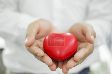 Photo for Man holding red heart shaped rubber. - Royalty Free Image