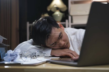 Photo for Exhausted businessman sleeping on his office desk, next to laptop and documents, tired of overworking. - Royalty Free Image
