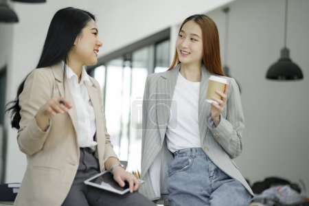 Photo for Two engaging businesswomen enjoying a casual conversation while holding coffee, illustrating a relaxed corporate culture. - Royalty Free Image