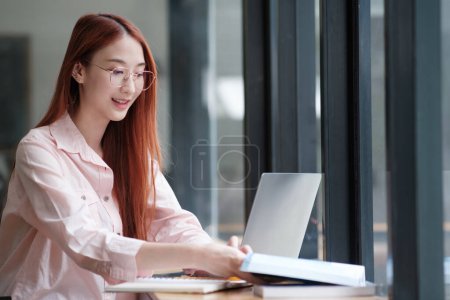 Photo for Young collage student using computer and mobile device studying online. Education and online learning. - Royalty Free Image