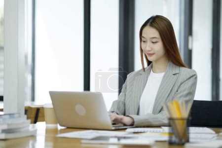 Photo for Business woman sitting working on her notebook with confidence and happiness doing a great job. - Royalty Free Image