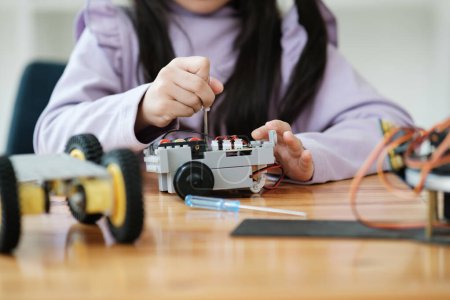 Téléchargez les photos : Asiatique fille se concentrant sur la construction d'un robot, incarnant l'éducation STIM. - en image libre de droit