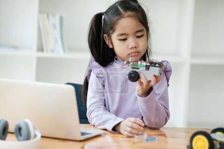 Photo for Asian girl concentrating on building a robot, embodying STEM education. - Royalty Free Image