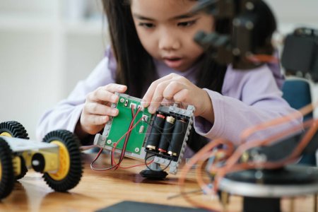 Foto de Chica asiática concentrándose en la construcción de un robot, encarnando la educación STEM. - Imagen libre de derechos