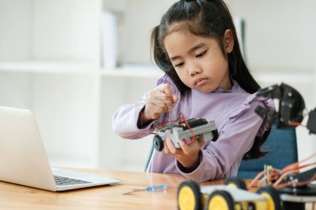 Téléchargez les photos : Asiatique fille se concentrant sur la construction d'un robot, incarnant l'éducation STIM. - en image libre de droit