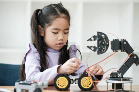 Foto de Chica asiática concentrándose en la construcción de un robot, encarnando la educación STEM. - Imagen libre de derechos