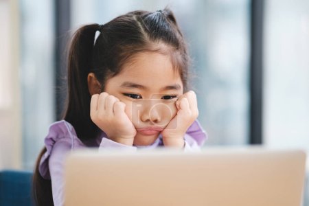 Foto de Una joven estudiante parece desinteresada y aburrida mientras participa en una clase en línea en su computadora portátil. - Imagen libre de derechos