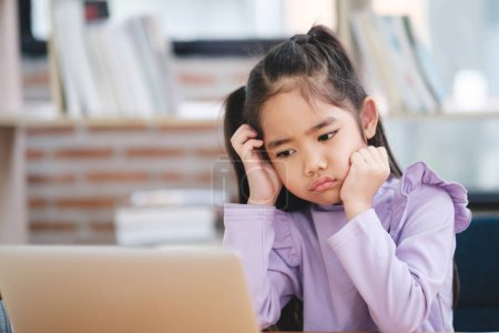 Photo for A young student appears disinterested and bored while engaging with an online class on her laptop. - Royalty Free Image