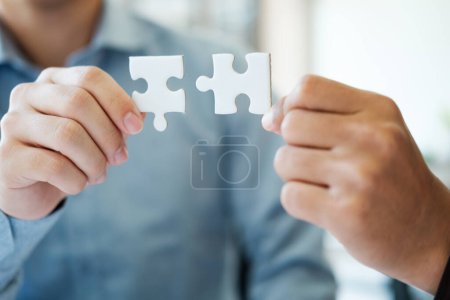 Photo for Two people holding a puzzle piece together. Concept of teamwork and collaboration. Scene is positive and uplifting, as it shows two people working together to solve a problem - Royalty Free Image