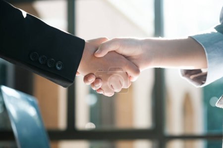 Photo for Two people shaking hands in a business setting. Scene is professional and formal. The handshake symbolizes agreement and trust between the two individuals - Royalty Free Image