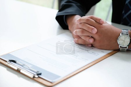 Photo for Close-up of a businessman's hands carefully examining a resume, focusing on qualifications for a job candidate. - Royalty Free Image