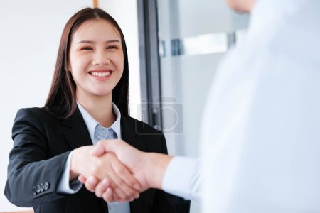 Téléchargez les photos : Une jeune femme d'affaires sourit tout en se serrant la main, faisant une impression positive lors d'une réunion professionnelle. - en image libre de droit
