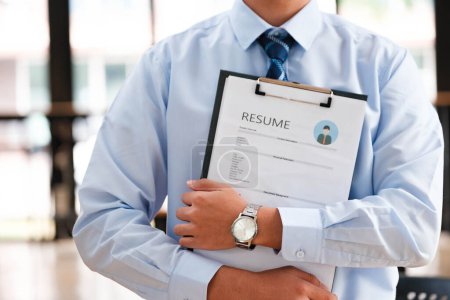 Primer plano de las manos de un hombre de negocios examinando cuidadosamente un curriculum vitae, centrándose en las cualificaciones para un candidato de trabajo.