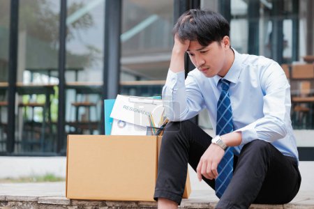 Photo for Disheartened Man Sitting on Stairs with Box of Personal Items, Overwhelmed by Emotions After Resignation or Job Loss - Royalty Free Image