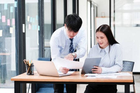 Foto de Compañeros de negocios asiáticos en discusión sobre análisis de datos digitales y de papel para la estrategia de crecimiento de la empresa en un escritorio de oficina. - Imagen libre de derechos