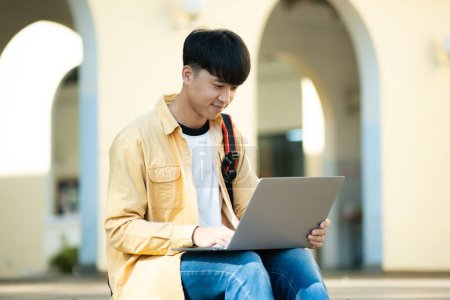 Photo for A university student is absorbed in thought while studying on his laptop, sitting at an outdoor table surrounded by the tranquility of the campus. - Royalty Free Image