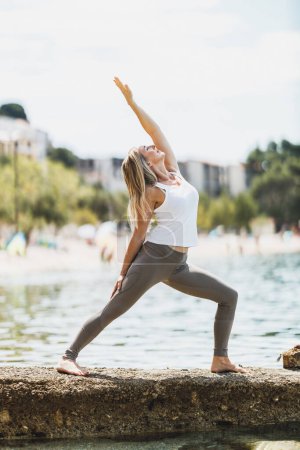 Téléchargez les photos : Fit middle age woman doing yoga exercises during training near the sea beach. - en image libre de droit