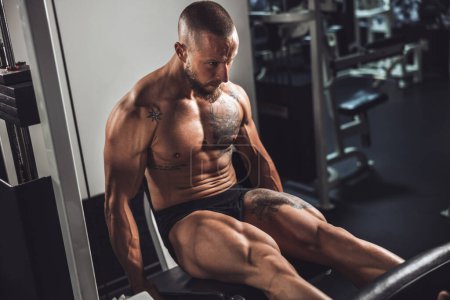 Téléchargez les photos : Un jeune homme musclé bodybuilder faire un entraînement dur pour ses muscles des jambes à la salle de gym. - en image libre de droit