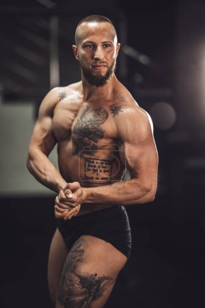 Téléchargez les photos : Prise de vue d'un jeune bodybuilder musculaire montrant ses muscles parfaits tout en posant après avoir travaillé à la salle de gym. - en image libre de droit