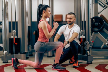 Téléchargez les photos : Young woman is doing training for legs with personal trainer in the gym. - en image libre de droit