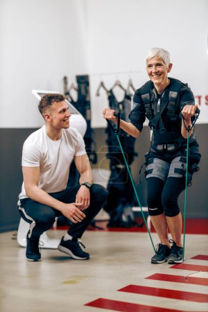 Téléchargez les photos : Femme âgée fait de l'entraînement EMS avec un entraîneur personnel dans la salle de gym. - en image libre de droit