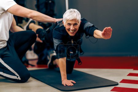 Foto de Mujer mayor está haciendo EMS entrenamiento con entrenador personal en el gimnasio. - Imagen libre de derechos