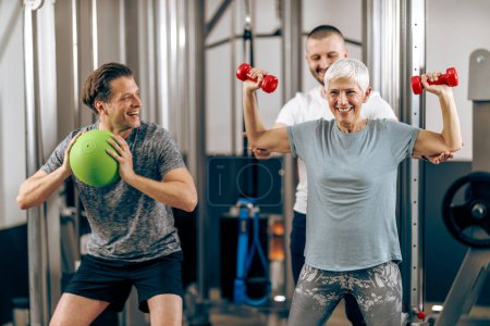 Photo for A senior mother and her middle age son have a workout in a gym. - Royalty Free Image