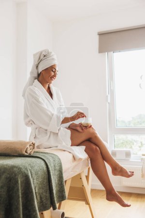 Téléchargez les photos : Belle jeune femme en peignoir et serviette de tête après un soin spa dans un salon de beauté. - en image libre de droit
