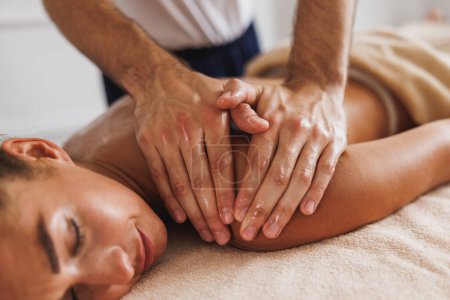 Téléchargez les photos : Gros plan d'une femme qui reçoit un massage relaxant du dos d'un professionnel au salon de beauté. - en image libre de droit
