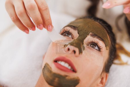 Téléchargez les photos : Jeune femme obtenir des patchs pour les yeux et le traitement du visage avec de la boue d'algues au spa. - en image libre de droit