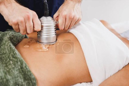 Photo for Unrecognizable woman getting an an ultrasound cavitation treatment to fat reduction on abdomen at the beauty salon. - Royalty Free Image
