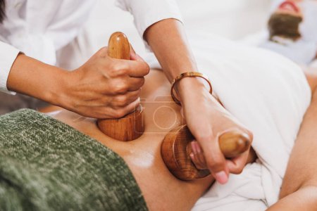 Photo for An unrecognizable woman getting anti cellulite maderotherapy massage with wooden cups at the beauty salon. - Royalty Free Image
